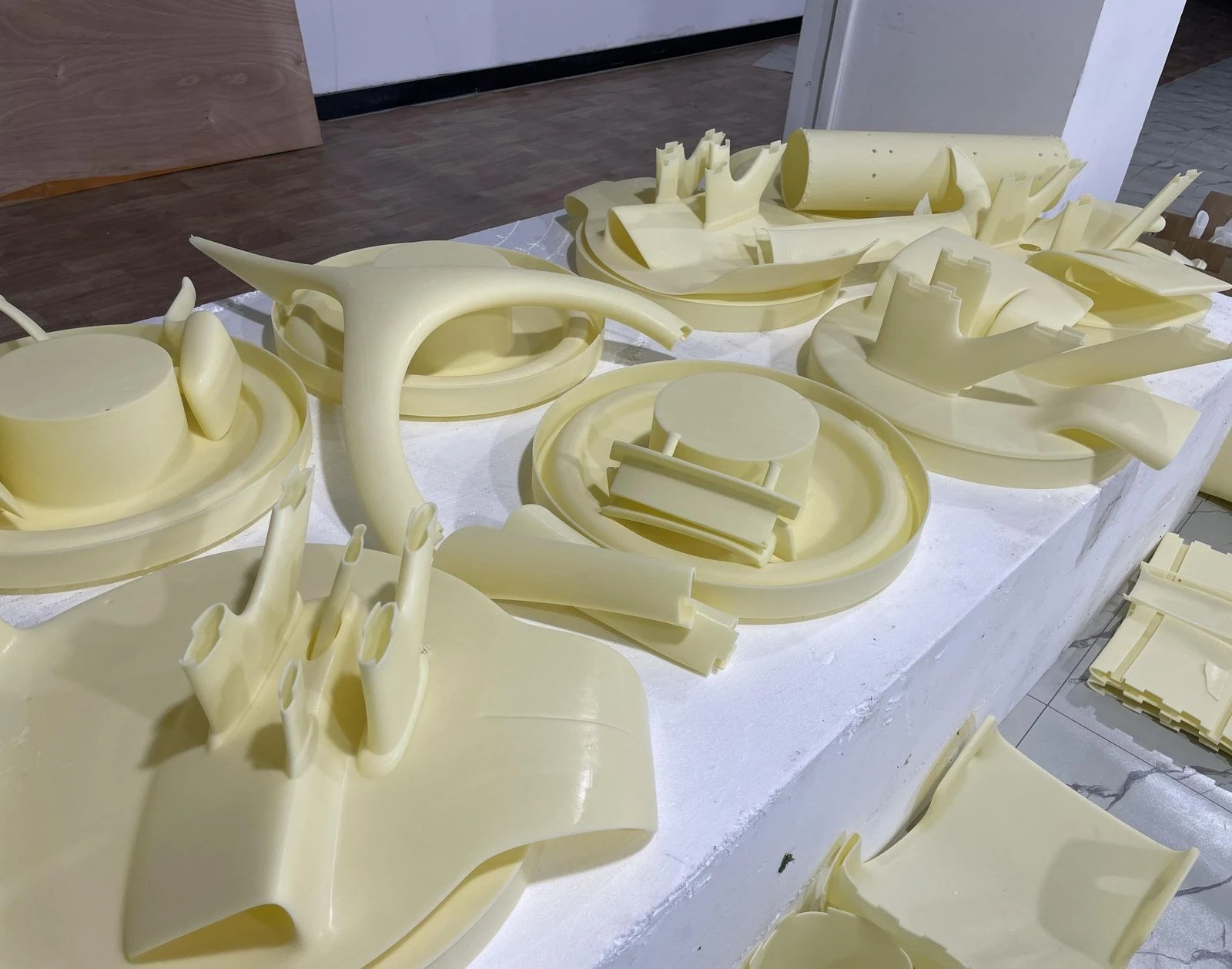 Pale 3D-printed master parts arranged on a workbench